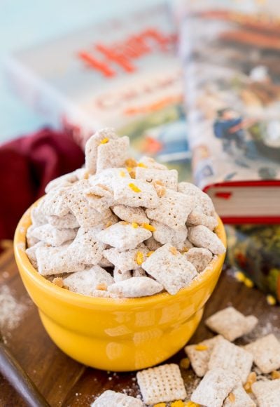 Butterbeer muddy buddies in a yellow bowl with Harry Potter books in the background.
