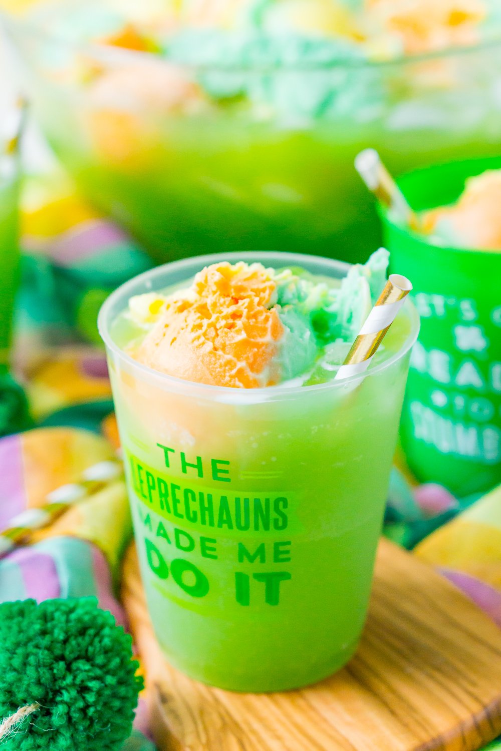 Cup of St. Patrick's Day Punch sitting in front of a punch bowl.