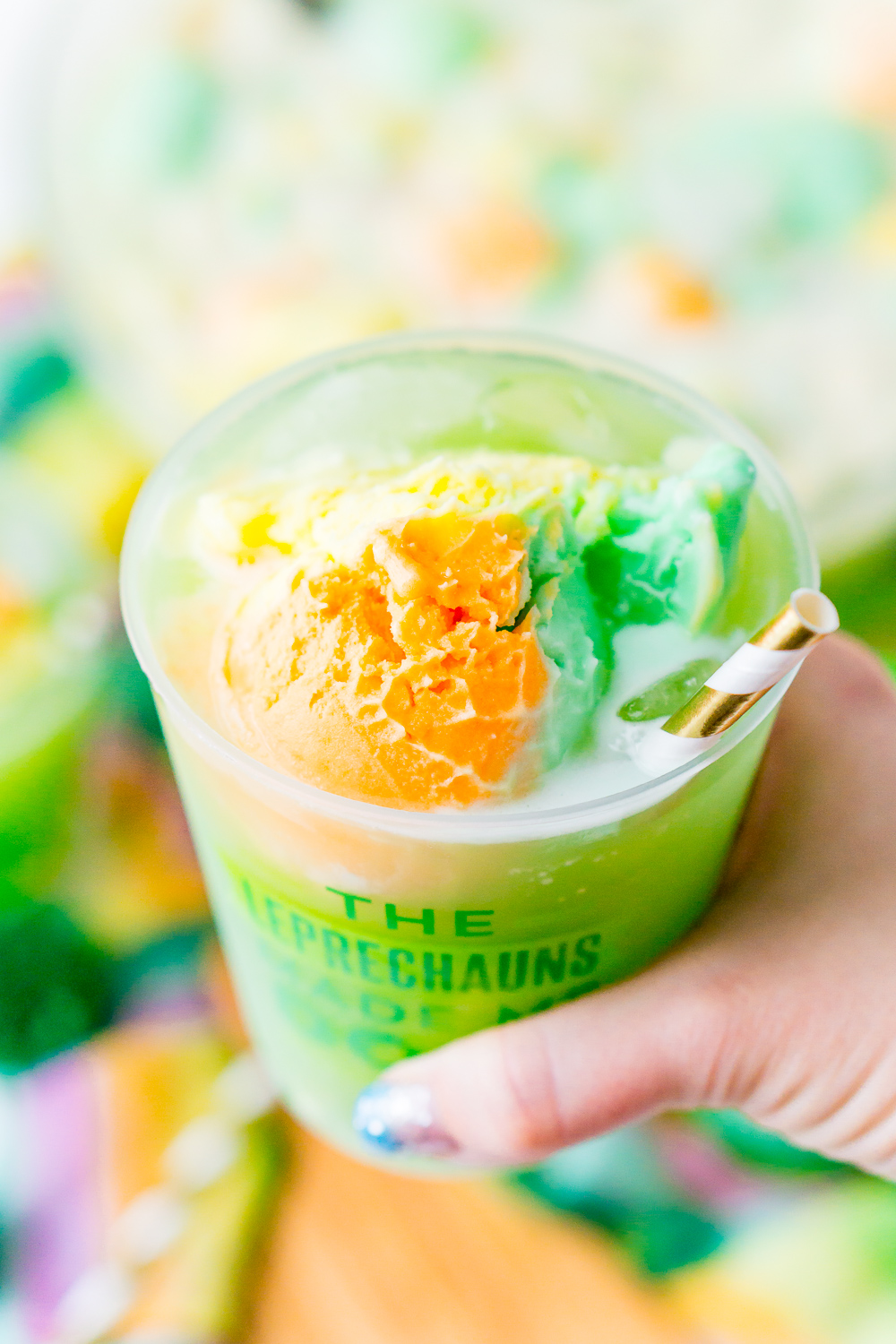 Woman's hand holding a cup of St. Patrick's Day Punch.