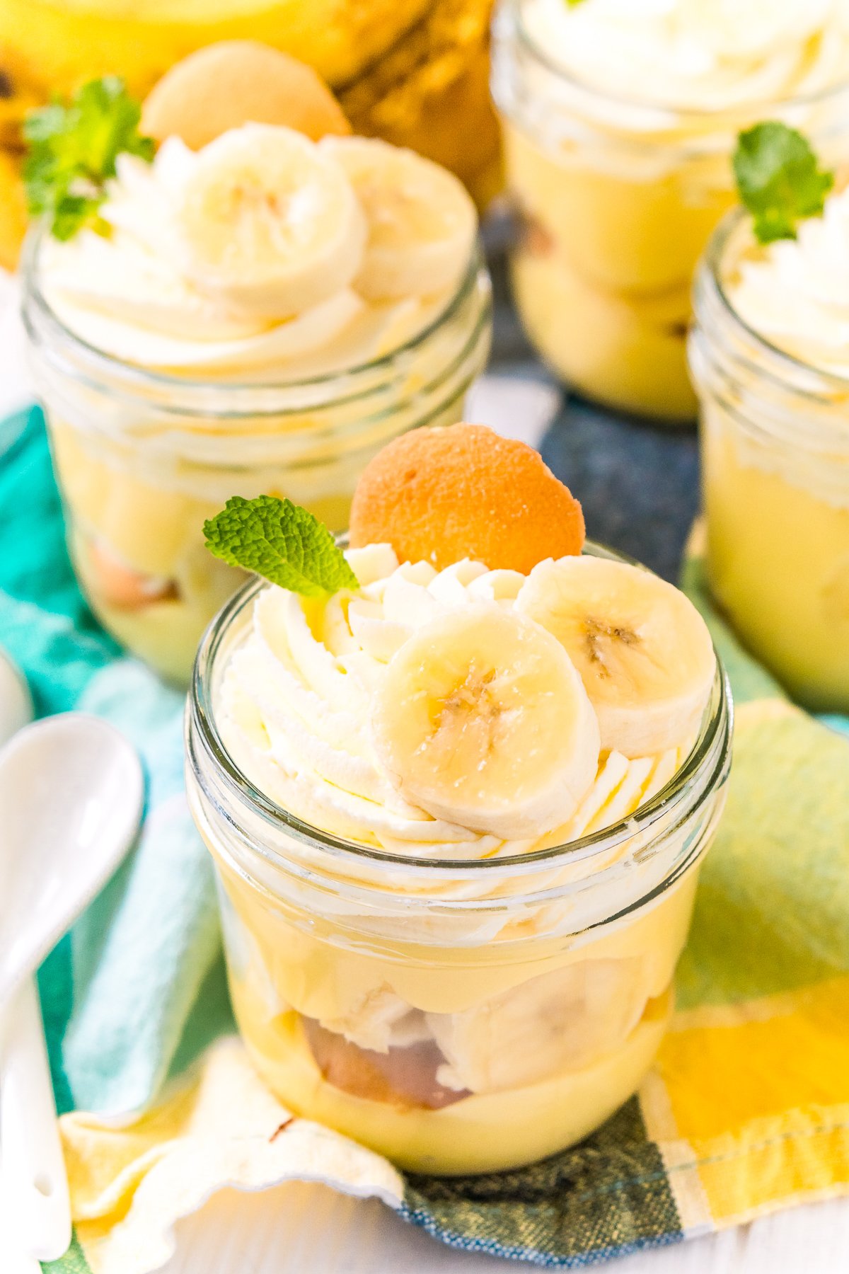 mini mason jars filled with banana pudding on a blue and yellow napkin.