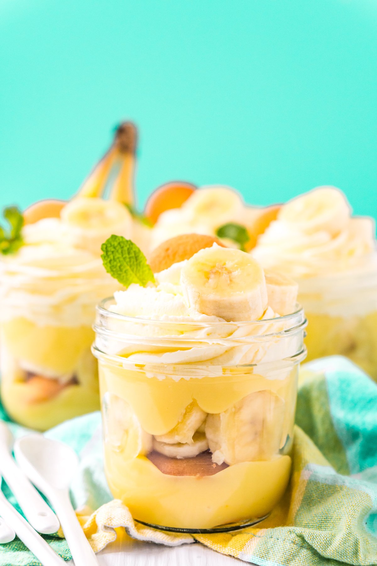 Jars of banana pudding ready to be served on a blue napkin.