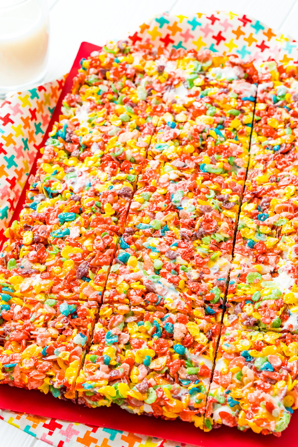 A sheet of fruity pebbles treats on a red cutting board. The treats have been cut but not pulled apart.