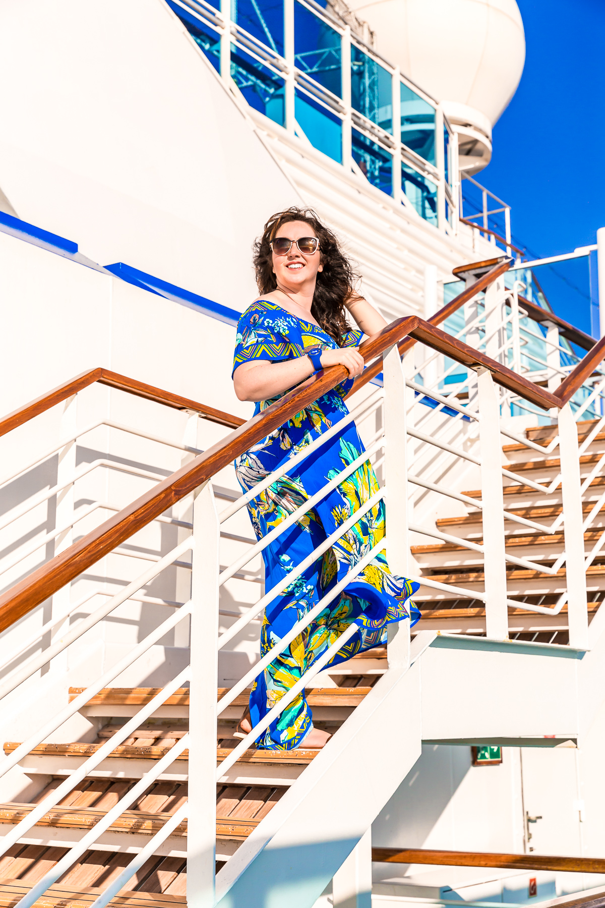 Woman in blue dress standing on stairs on a cruise ship.