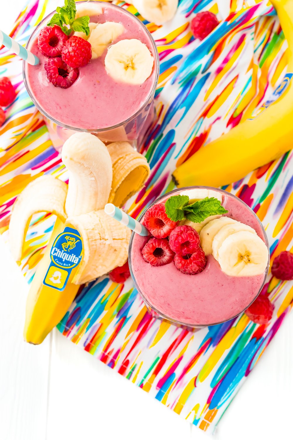 Overhead shot of two glasses filled with raspberries banana smoothies.