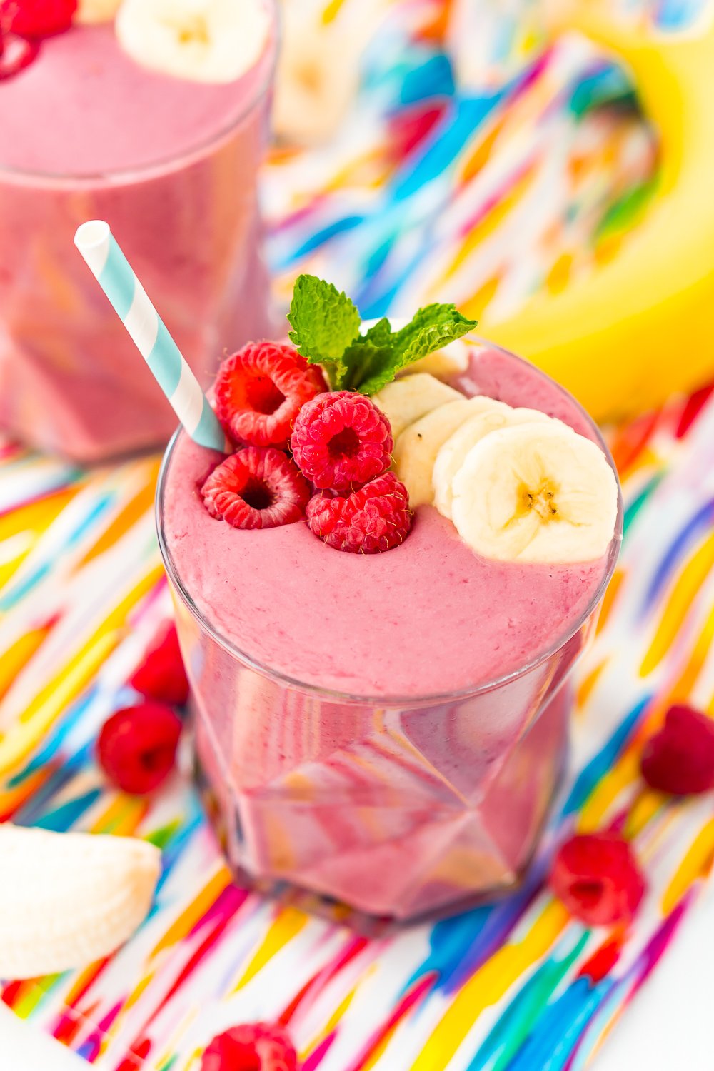 Raspberry Banana Smoothie topped with banana slices, mint, and fresh raspberries.