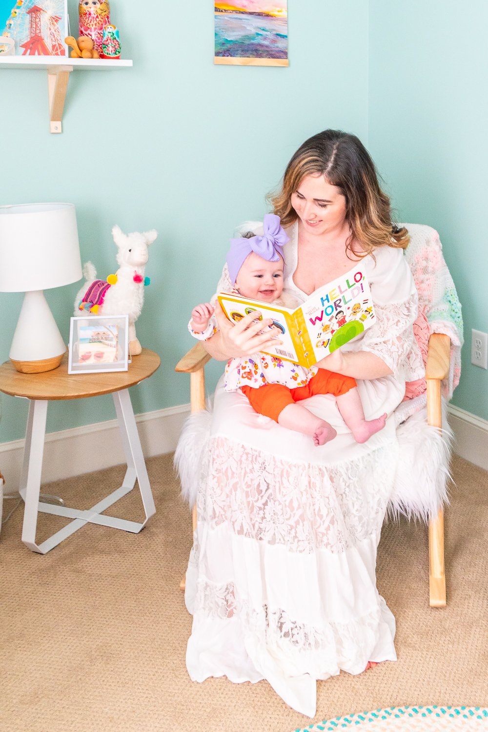 Woman reading book to her baby daughter in rocking chair.