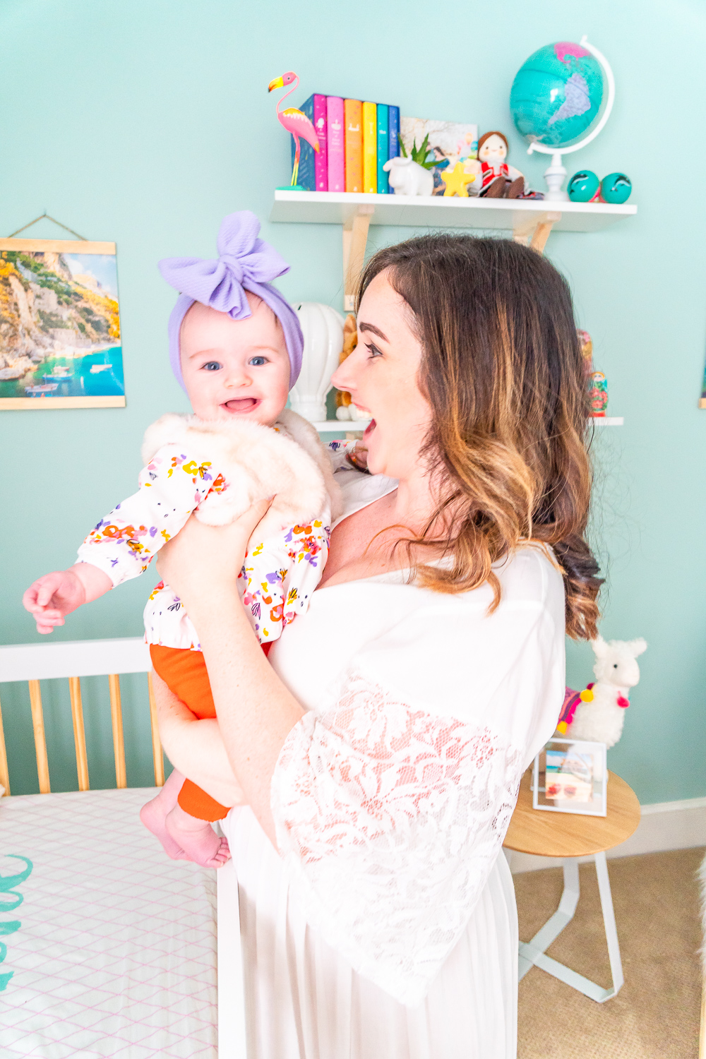 Mother and daughter standing by crib in travel inspired nursery.