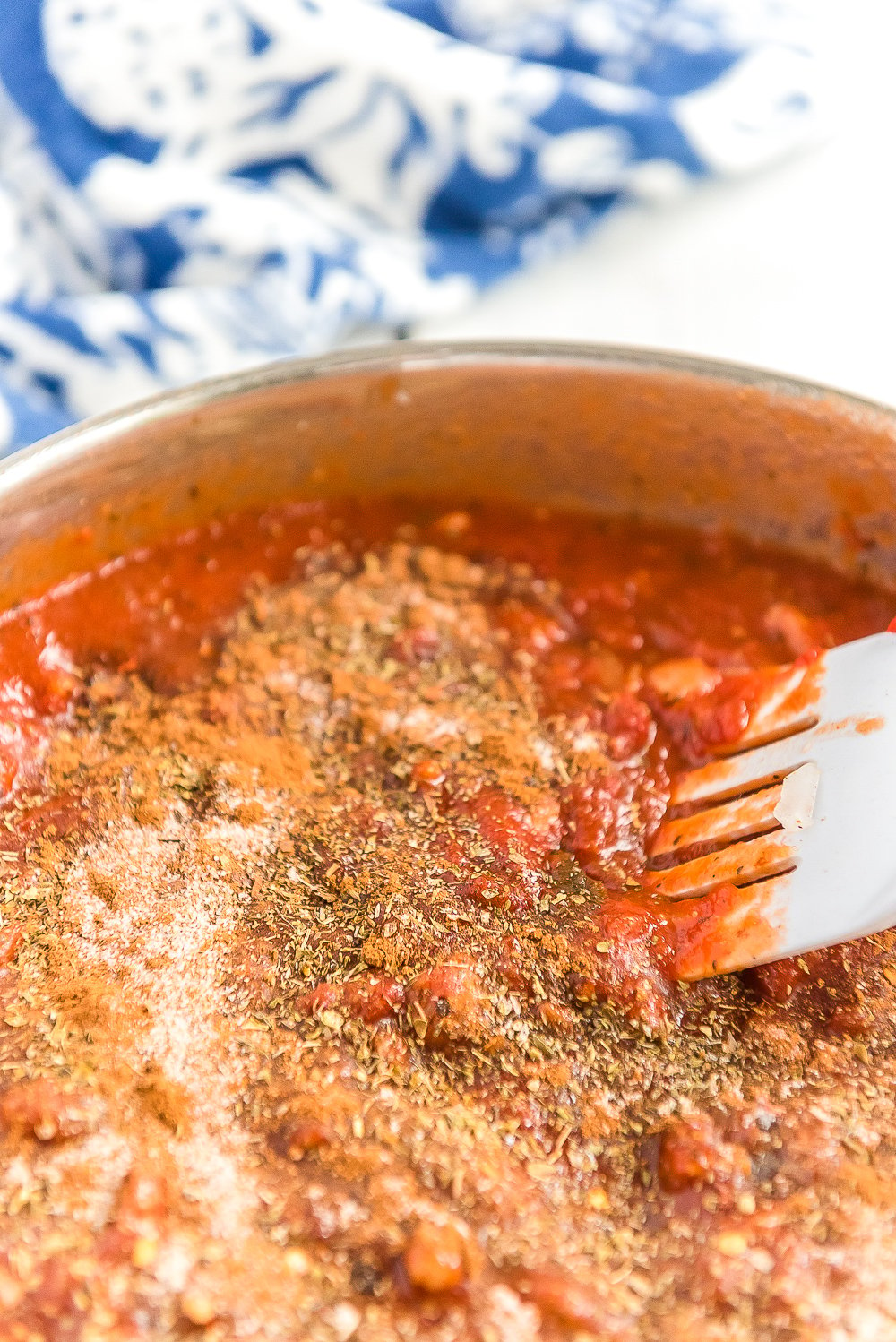 Red sauce with spices being simmered in a skillet.