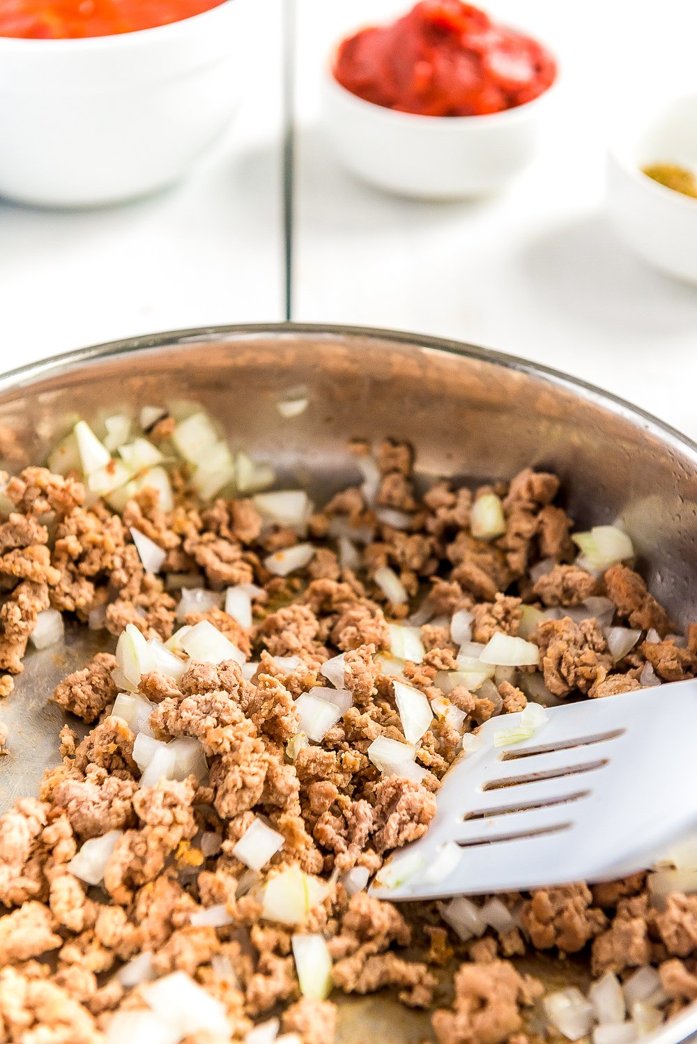 Ground turkey and diced onions being browned in a skillet.