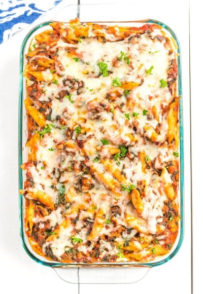 Casserole dish with turkey florentine pasta bake in it on white wood table.