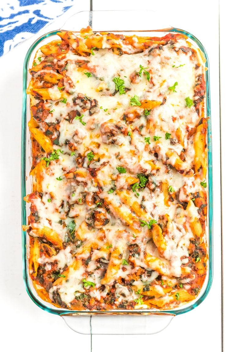 Casserole dish with turkey florentine pasta bake in it on white wood table.