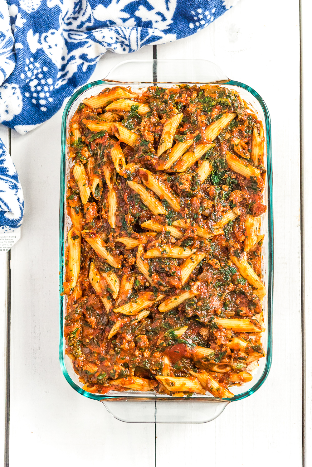 Turkey Florentine pasta bake in a casserole dish on a white table with blue napkin.