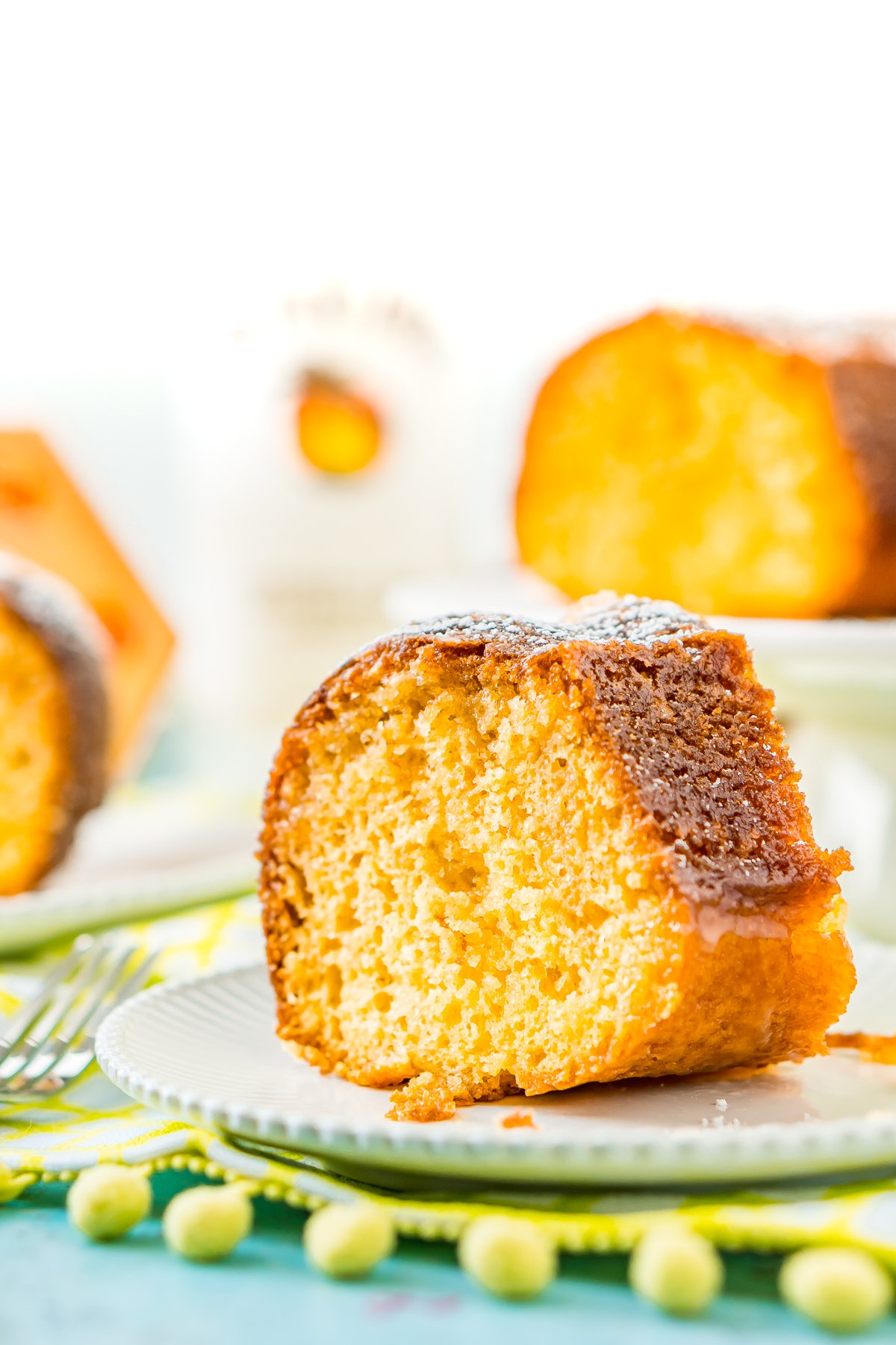 Slice of rum cake on a white cake with more slices on the background.