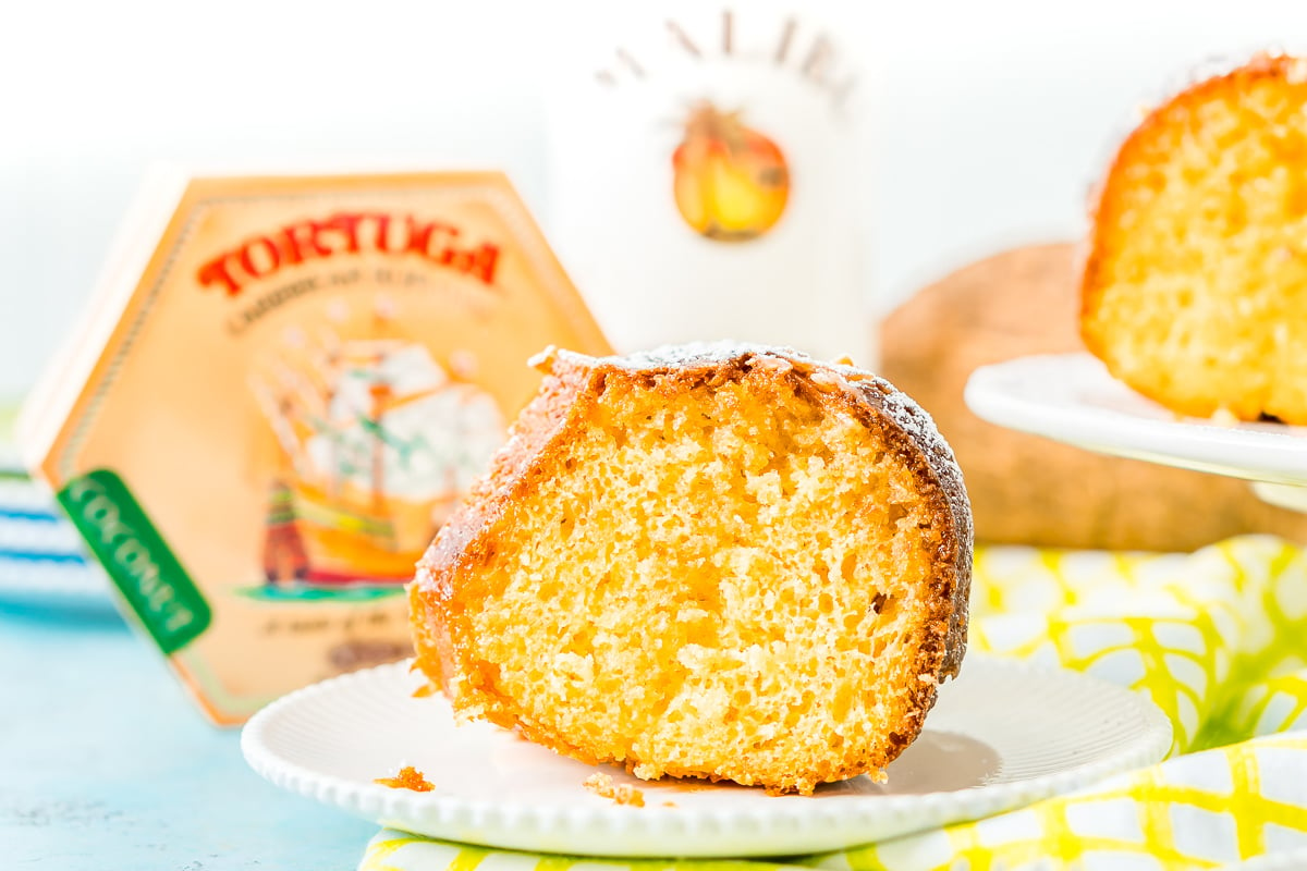 Slice of rum cake on a white plate with a Tortuga Rum Cake box in the background.