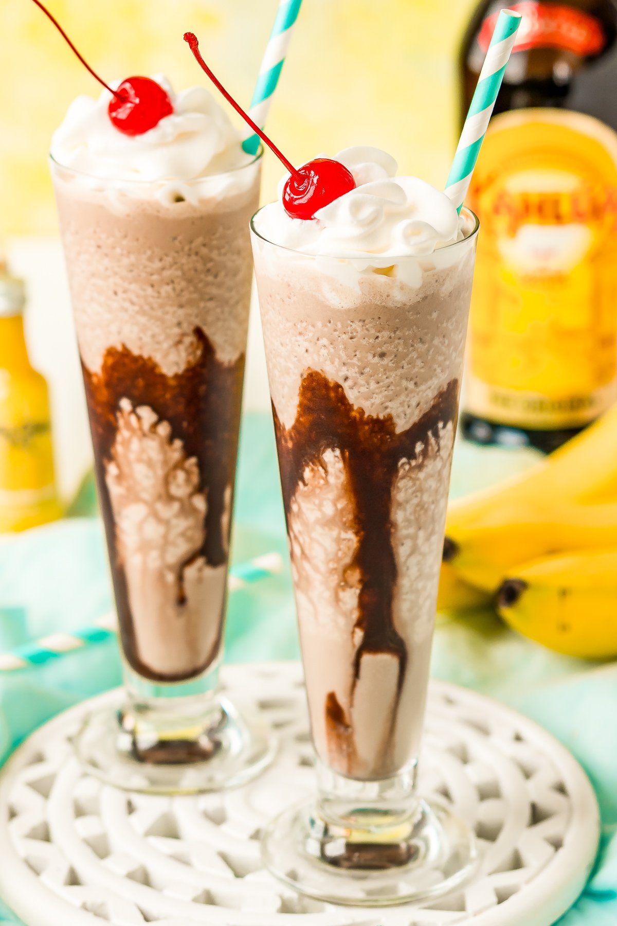 Close of photo of dirty banana cocktails with a bottle of kahlua in the background.