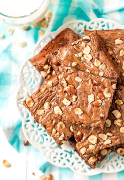 Brownies with chopped hazelnuts on a white plate with a blue and white napkin.