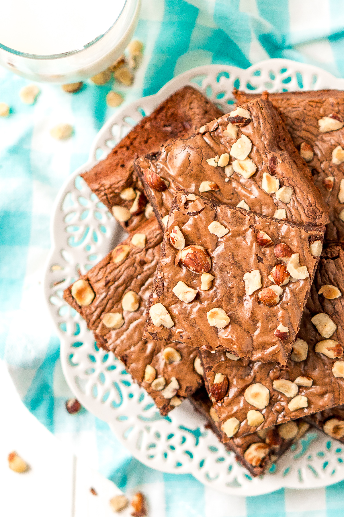 Brownies with chopped hazelnuts on a white plate with a blue and white napkin.