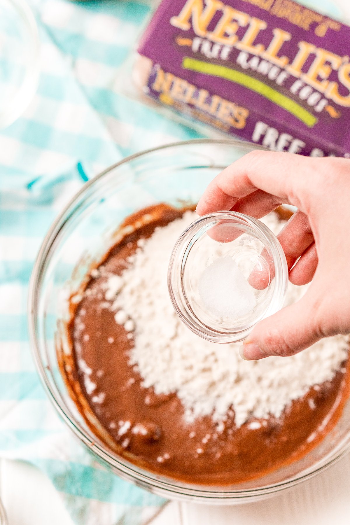 Salt being added to a bowl of brownie mix and flour.