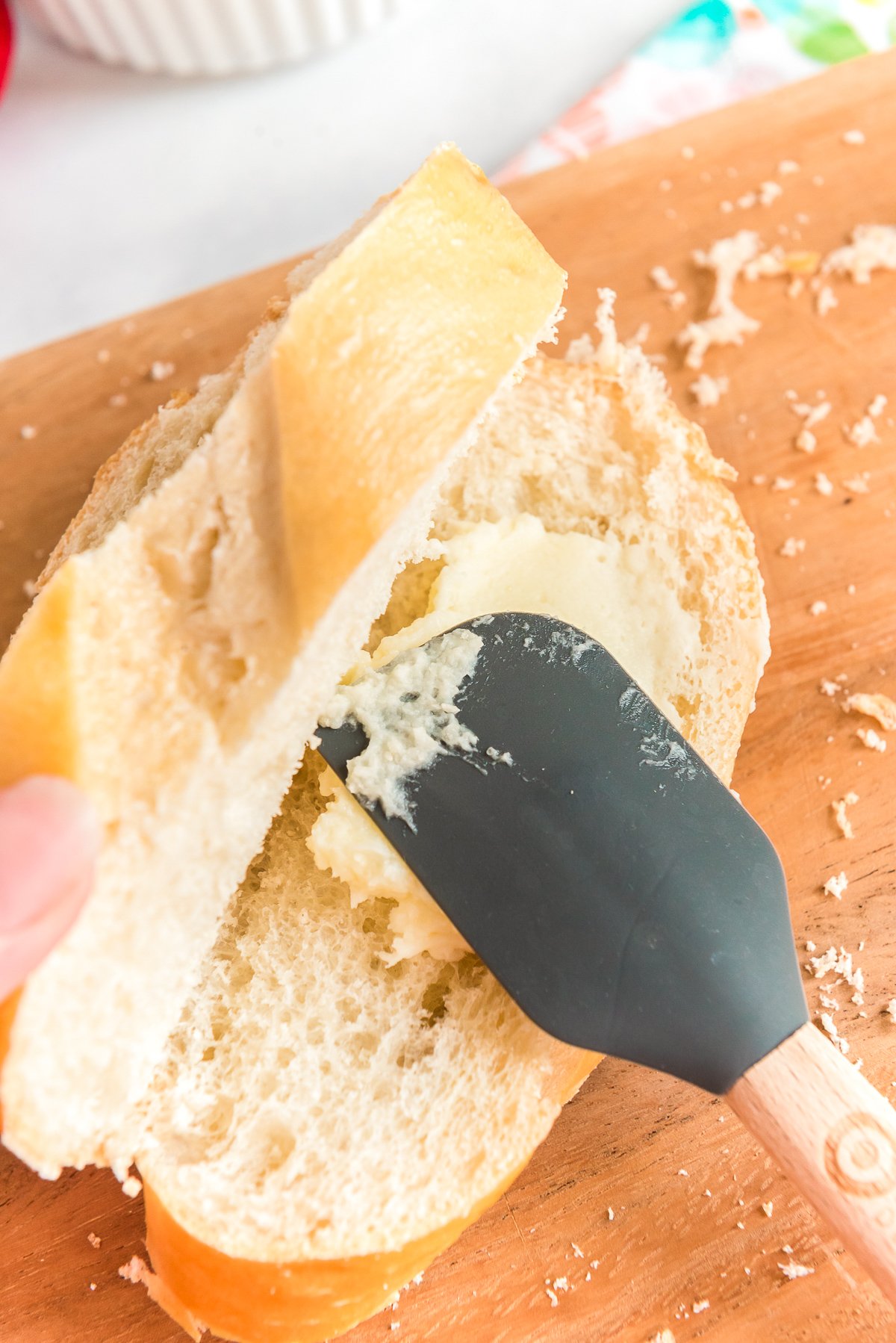 Mascarpone cheese filling being spread on french bread with a rubber spatula.