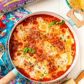 Overhead photo of Eggs In Purgatory in a skillet with additional ingredients scattered around it.