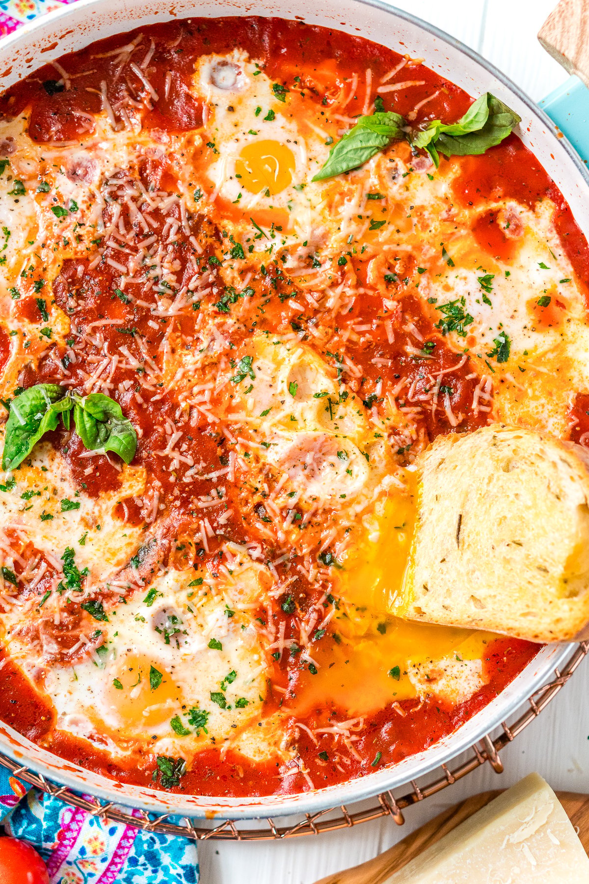 Overhead photo of a slice of bread being dipped in a runny egg yolk in a poached egg dish.