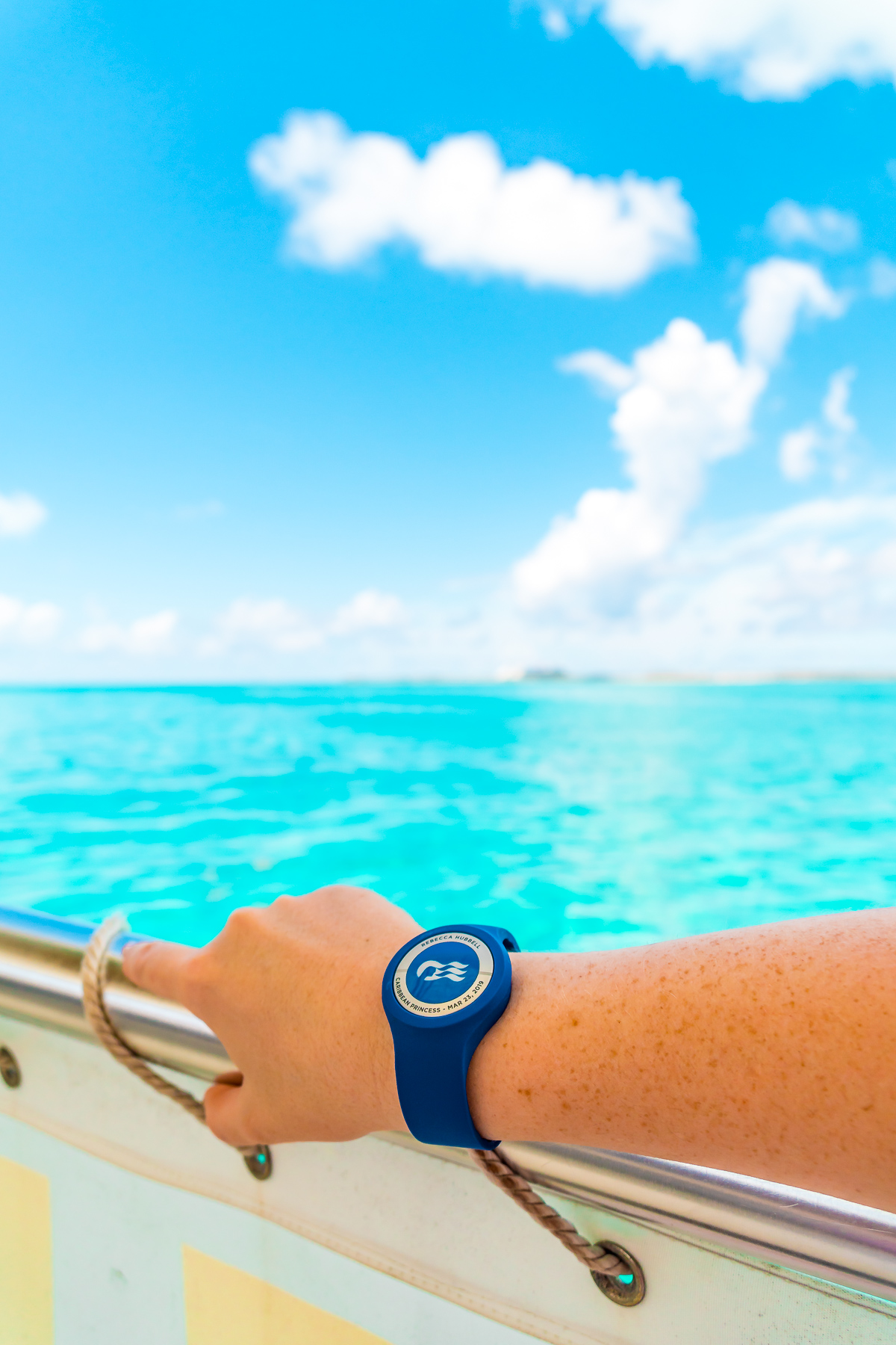 Princess Cruises Ocean Medallion watch on a woman's arm on a boat overlooking the Caribbean.