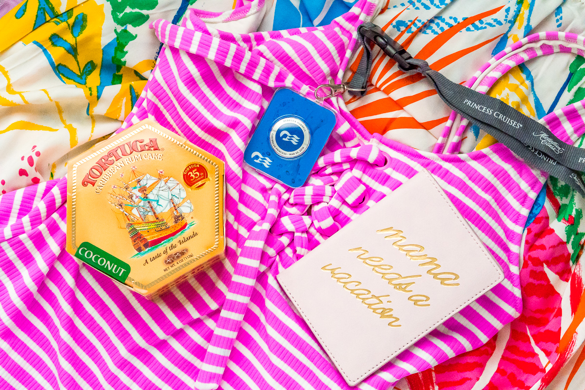 Rum cake, princess medallion, and passport laying on a pink and white striped bathing suit.