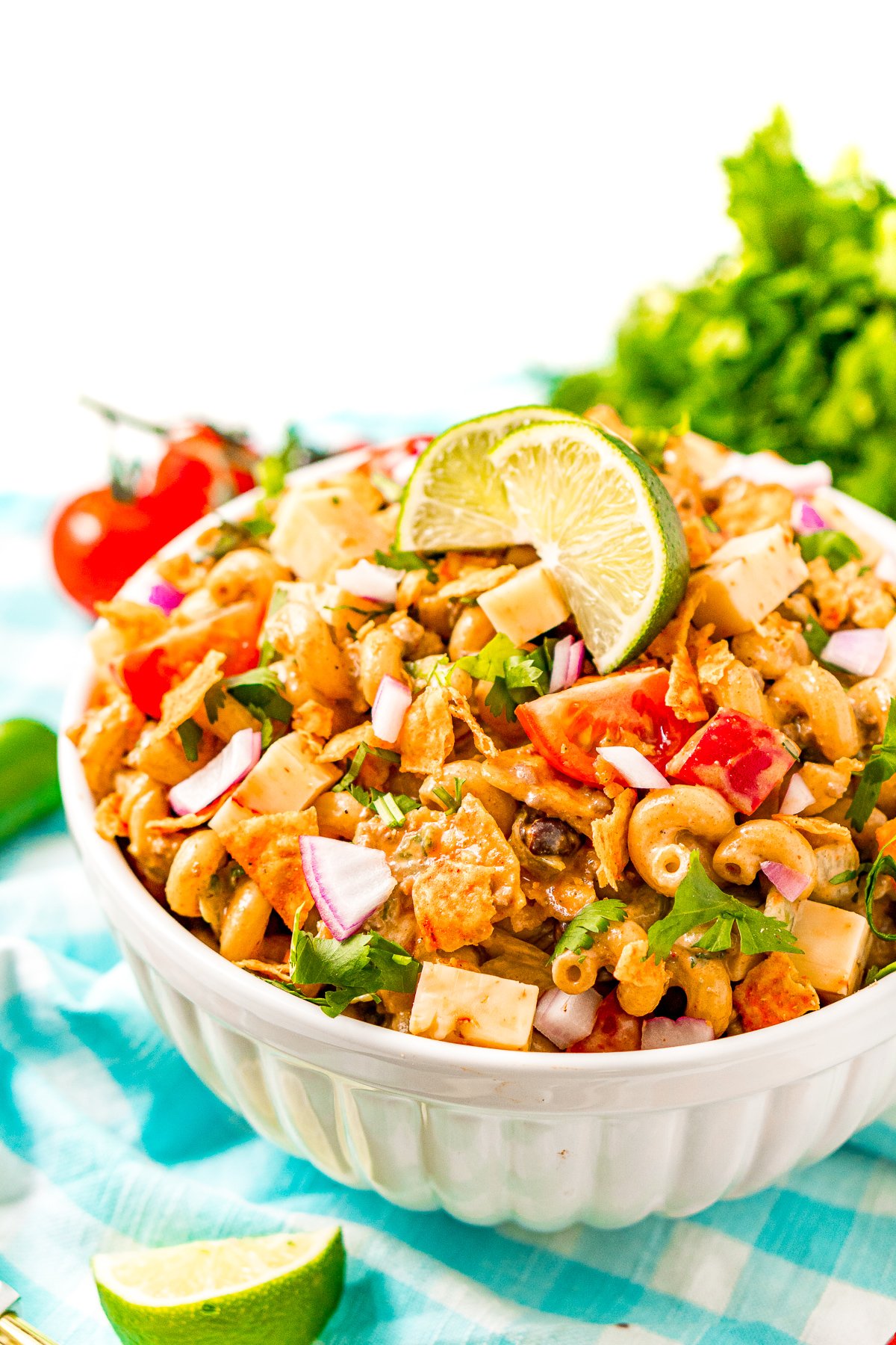 Taco pasta salad in a white bowl on a blue checkered napkin.