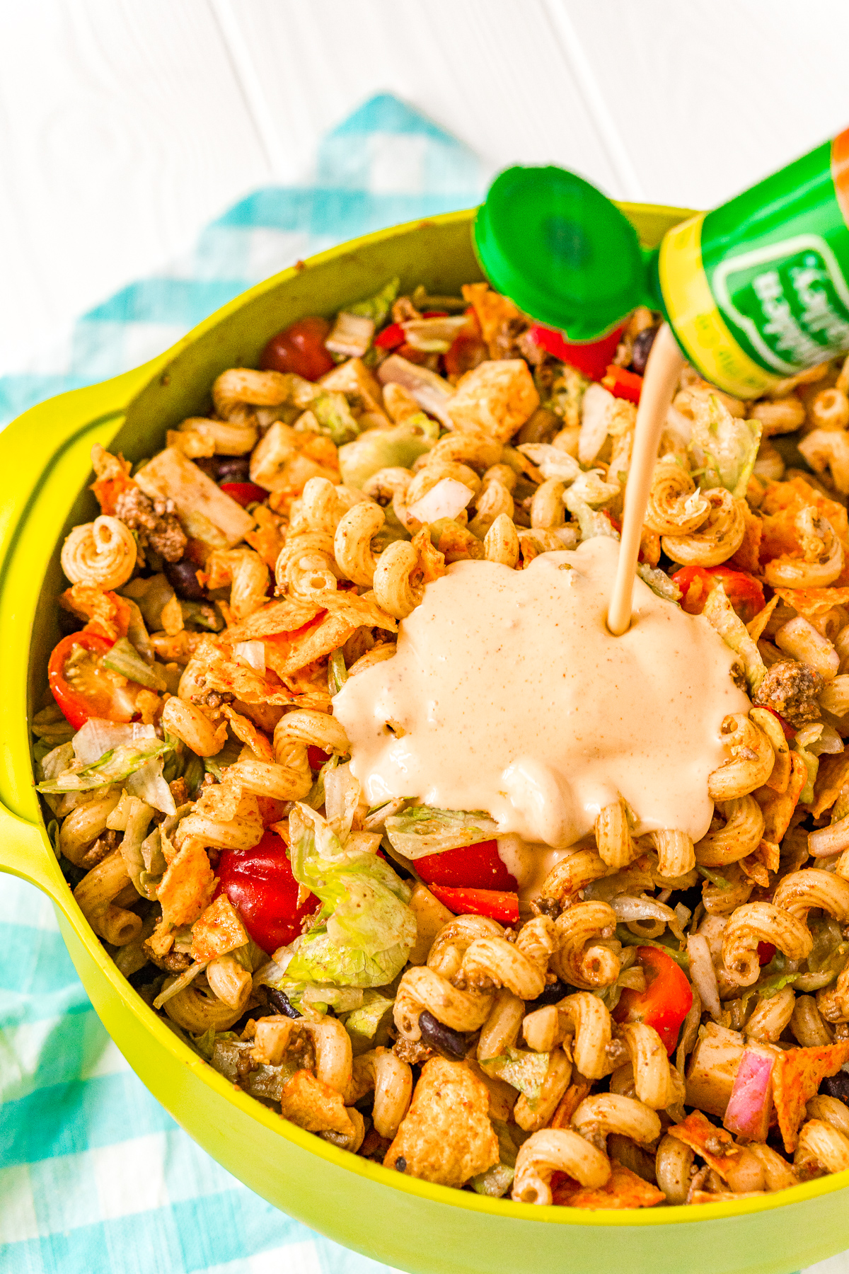 Dressing being added to a bowl of taco flavored pasta salad.