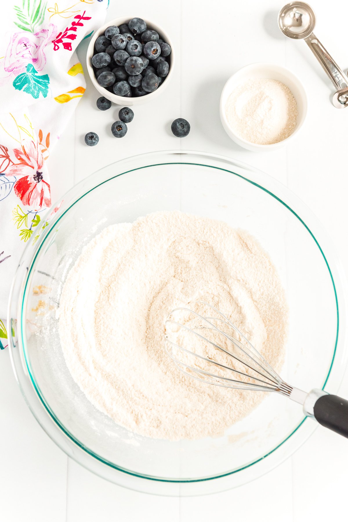 Flour, salt, and sugar being whisked together in a large glass bowl.