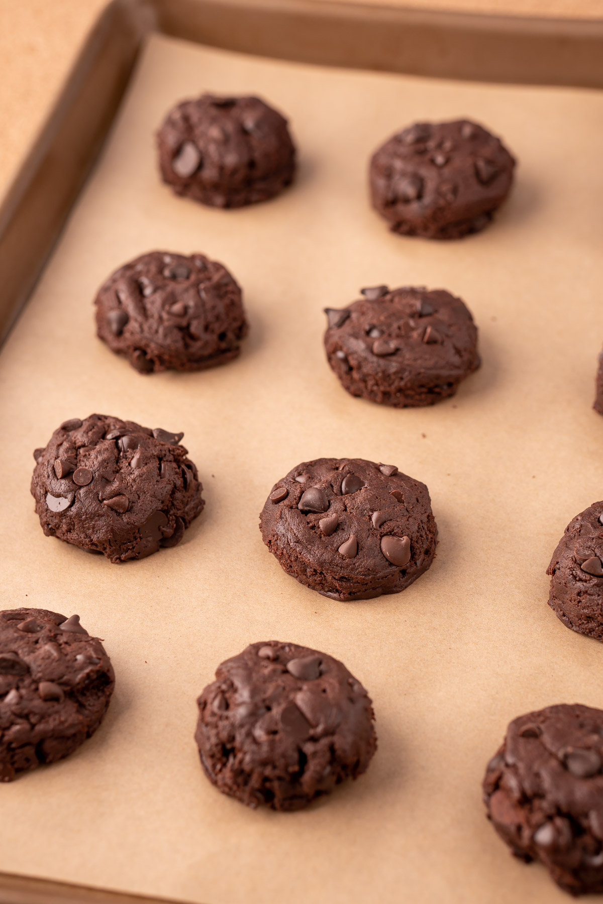 Double chocolate chip cookies on a baking sheet lined with parchment paper ready to bake.