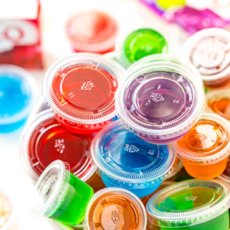 Multi colored jello shots in a white bowl.