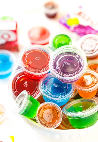 Multi colored jello shots in a white bowl.