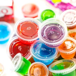 Multi colored jello shots in a white bowl.