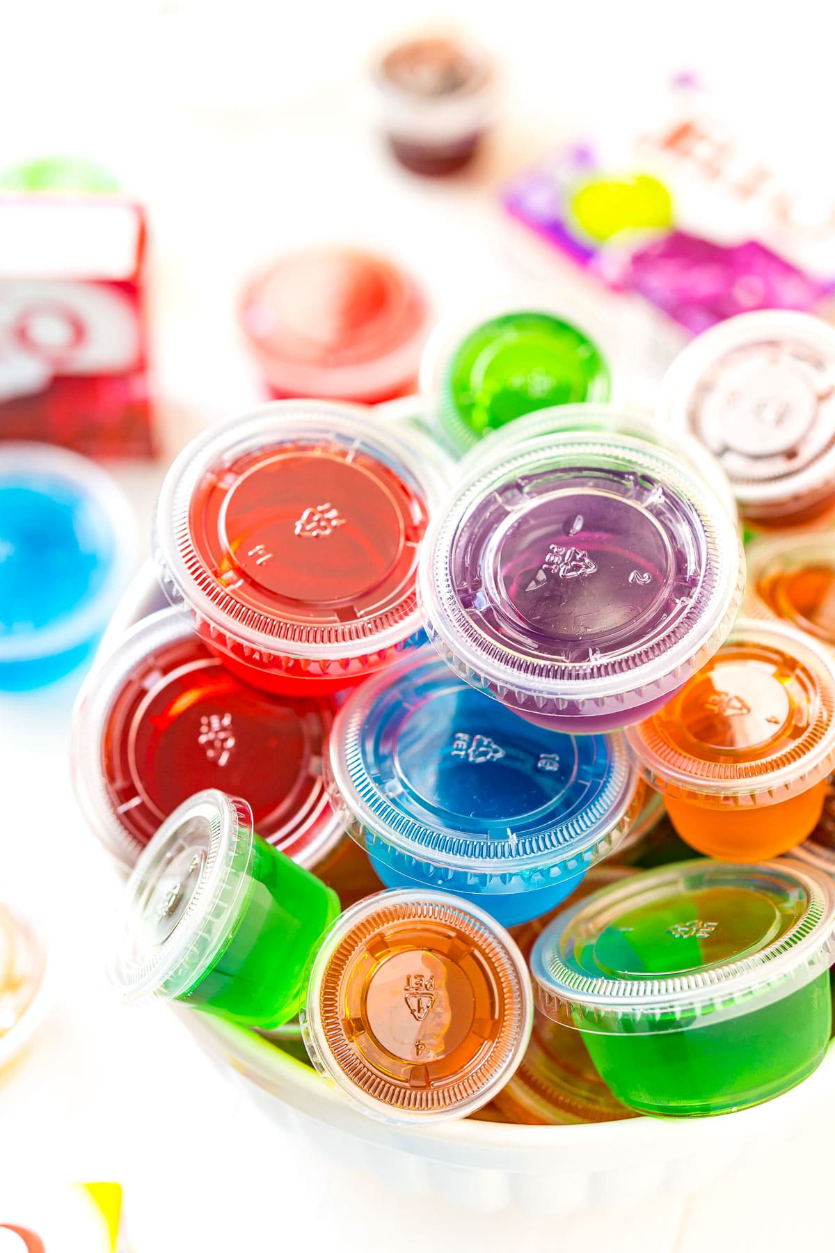 Multi colored jello shots in a white bowl.