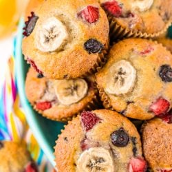 Muffins with banana and berries piled in a teal bowl.