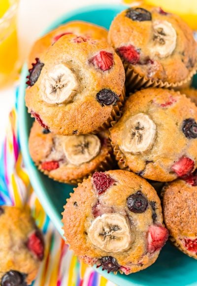 Muffins with banana and berries piled in a teal bowl.