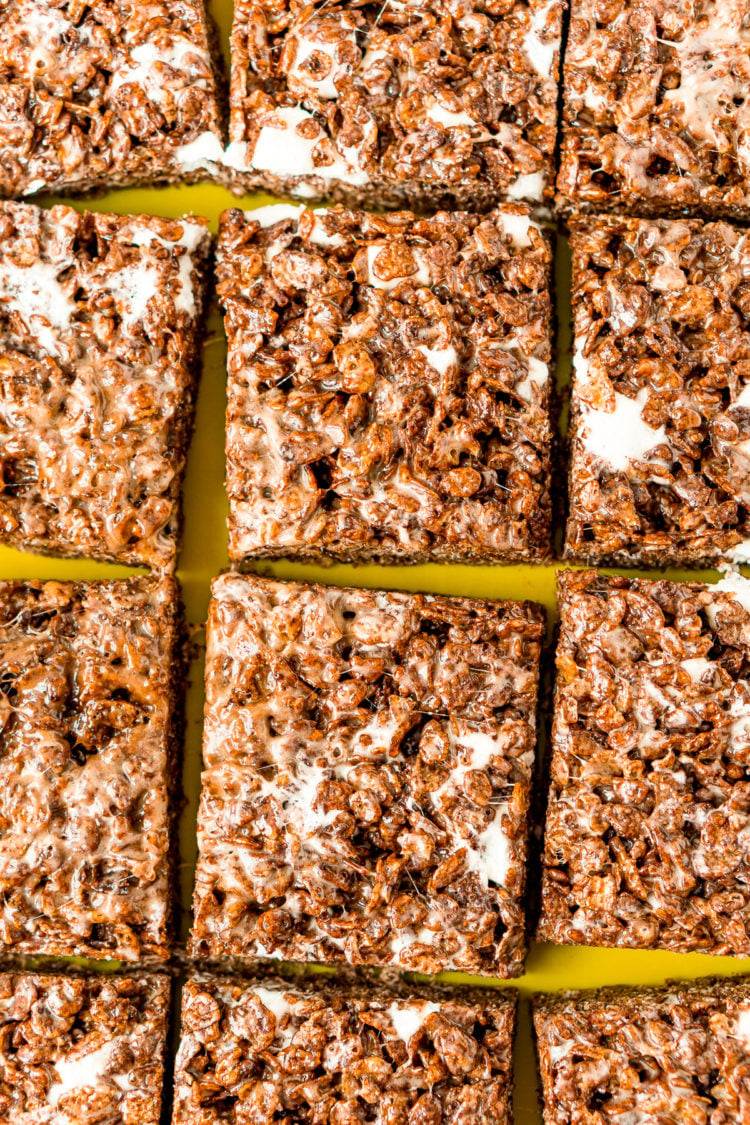 Cocoa Pebbles Treats sliced into squares on a green cutting board.