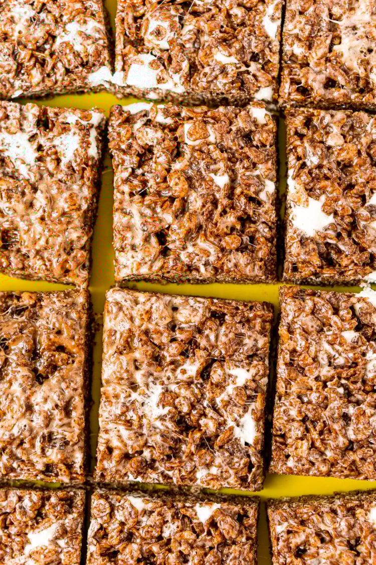 Cocoa Pebbles Treats sliced into squares on a green cutting board.