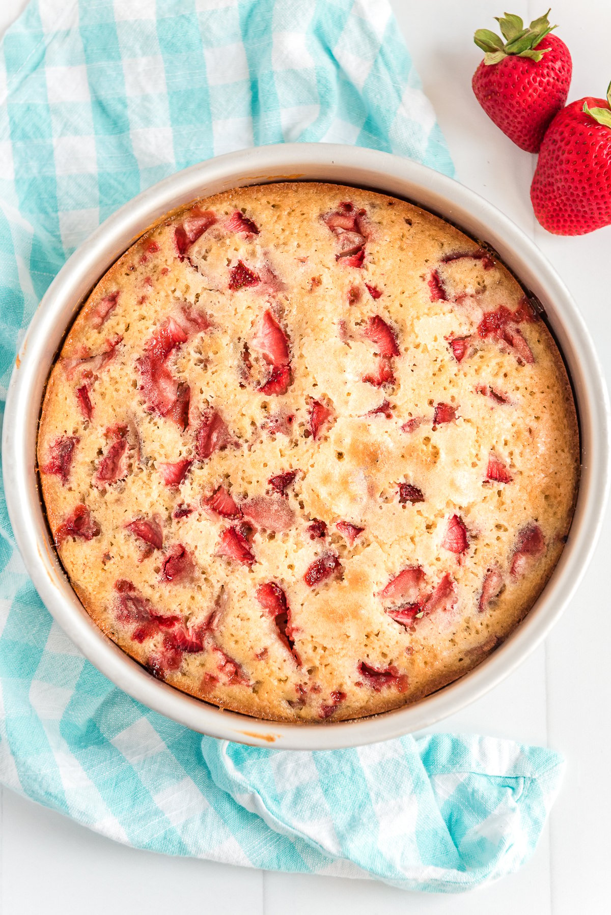 Overhead photo of baked strawberry cake on a blue napkin.