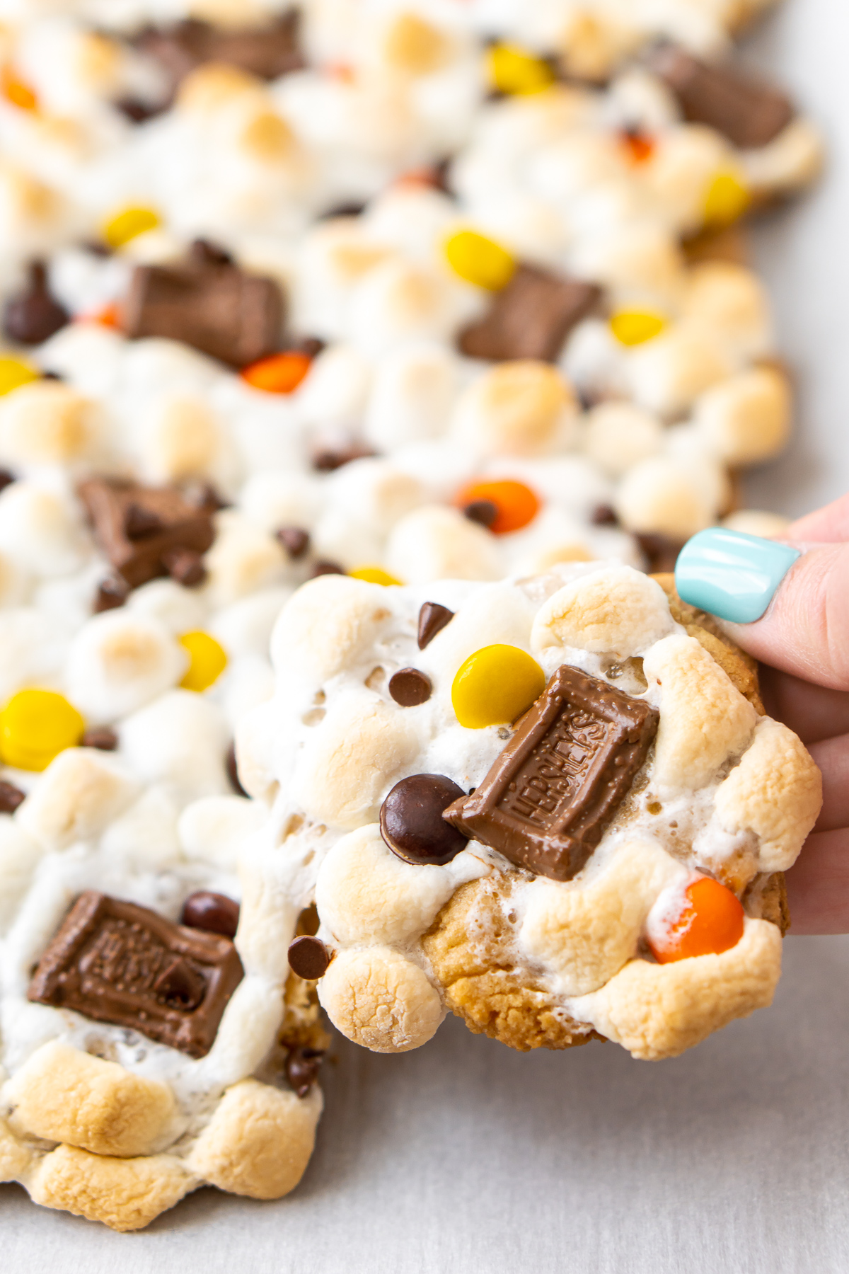 Woman's hand pulling a smores bar from a pan.