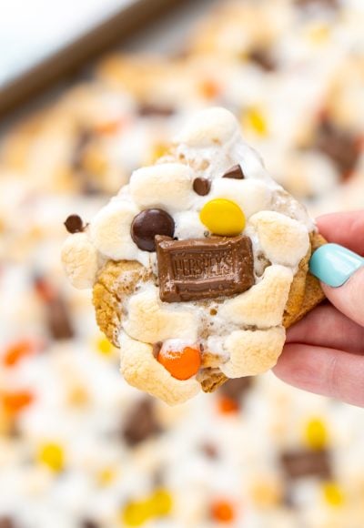 Close up photo of a woman's hand holding a peanut butter s'mores bar.