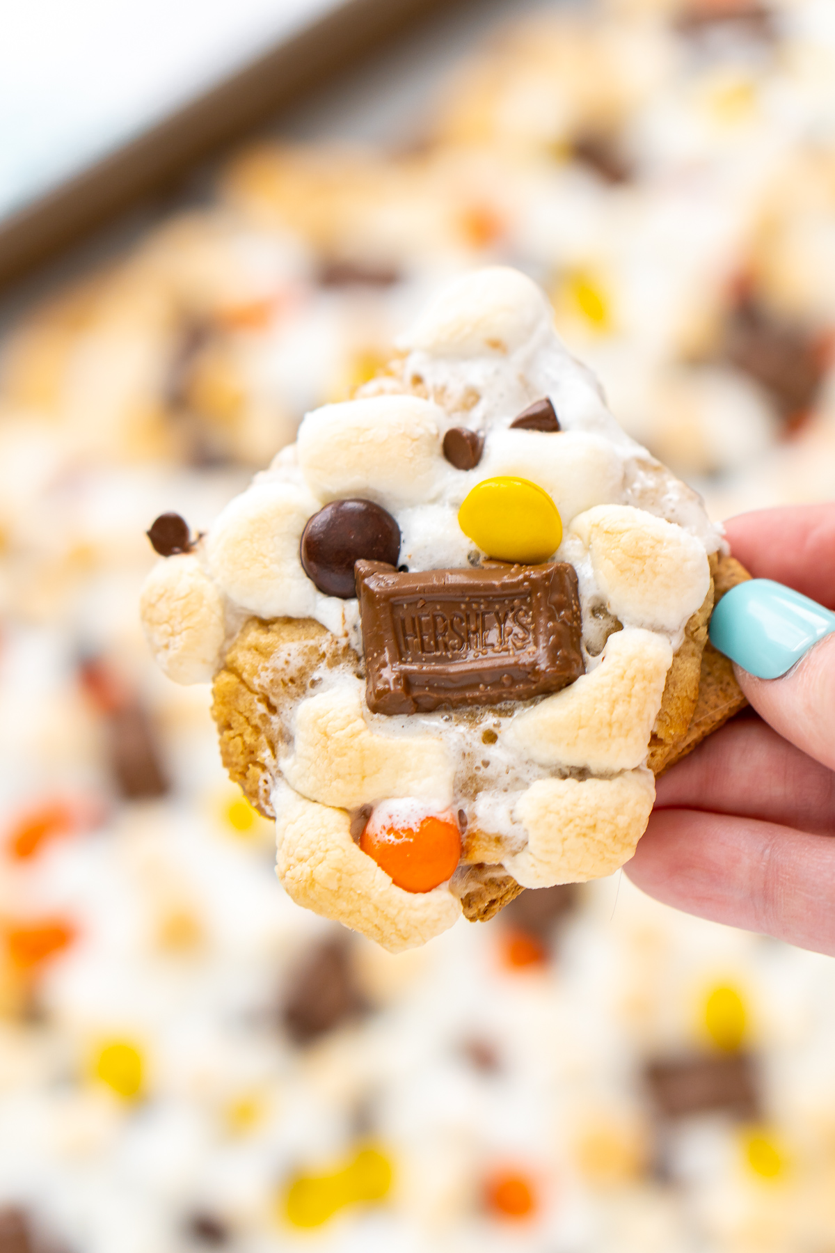 Close up photo of a woman's hand holding a peanut butter s'mores bar.