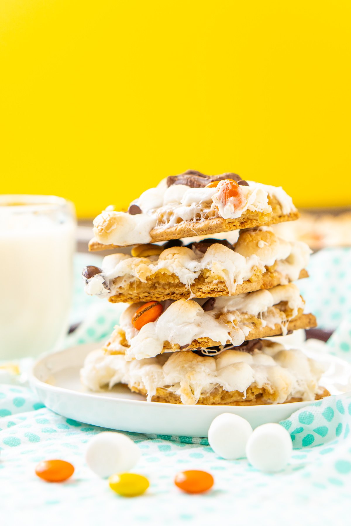 Stack of smores bars on a white plate with a yellow background.