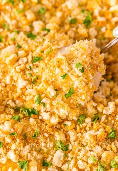 Close up photo of a chicken breast being scooped out of a chicken and rice casserole.