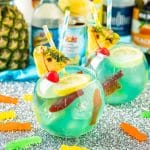 Individual fish bowl drinks with bottles of alcohol in the background.