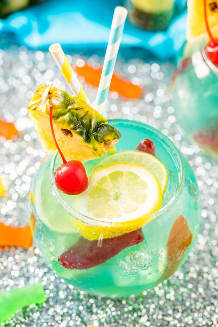 Close up photo of a fish bowl drink on a silver sparkling table.