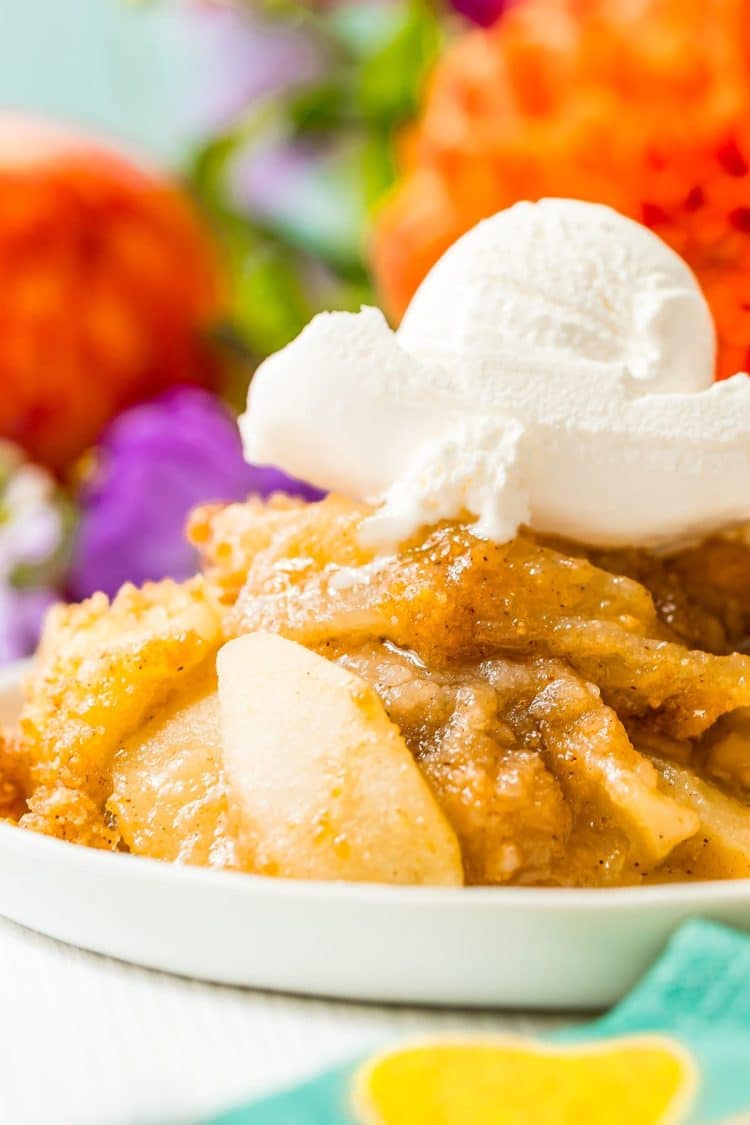 Close up photo of apple brown betty on a white plate topped with ice cream.