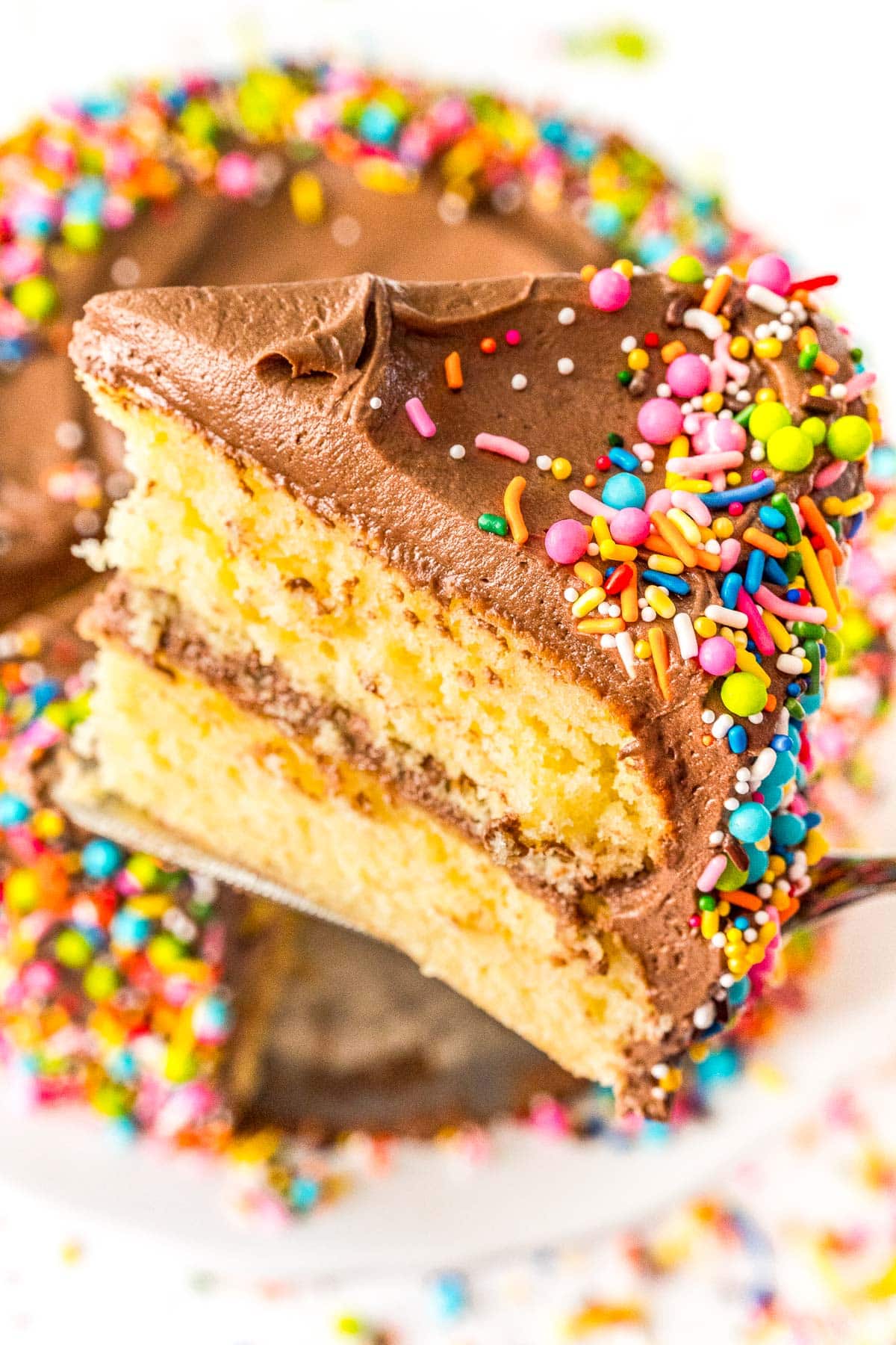 Slice of yellow layer cake being lifted with a cake server from the cake.