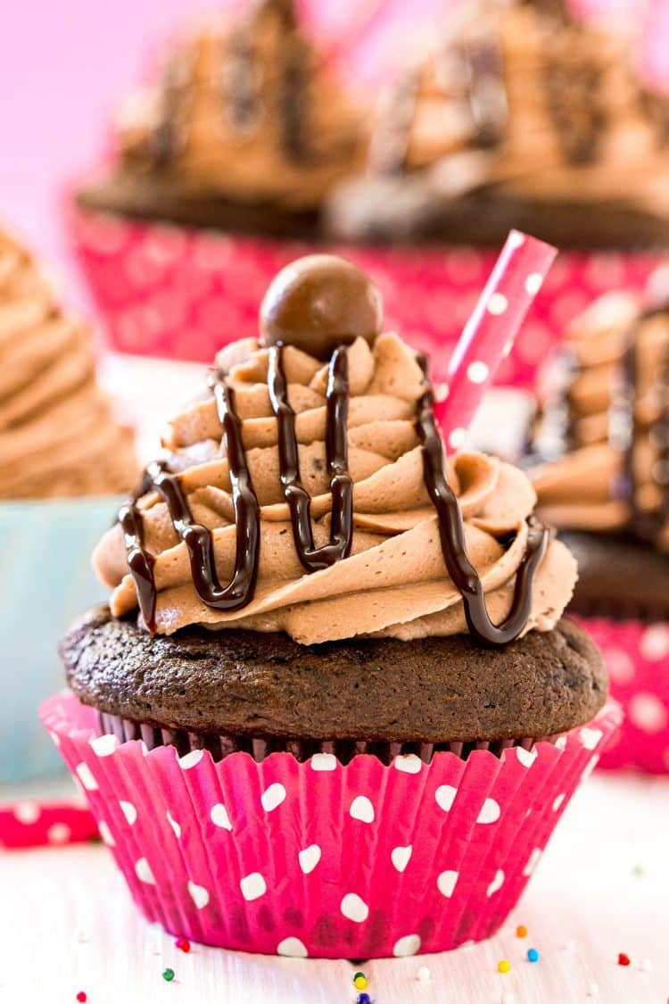 Close up photo of a chocolate milkshake cupcake with more cupcakes behind it.